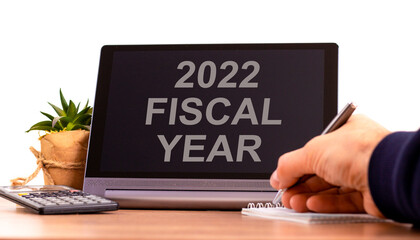 2022 fiscal new year symbol. Tablet with words 'fiscal year'. Businessman hand with pen, house plant. Copy space. Beautiful white background. Business and 2022 fiscal new year concept.