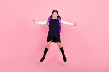 Full length body size photo schoolgirl jumping up with backpack smiling isolated pastel pink color background