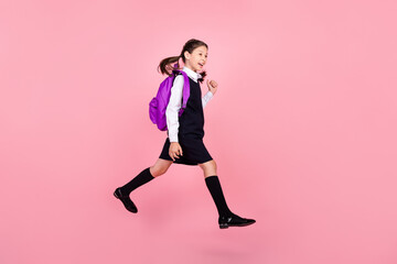 Fototapeta na wymiar Full length body size photo schoolgirl jumping keeping backpack walking to school isolated pastel pink color background