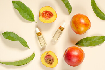Natural peach oil. Two bottles with essential peach oil, peaches and green peach leaves on a beige background. Natural cosmetics, hair care