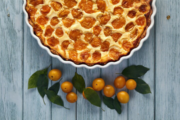 Delicious cherry plum pie in a cream filling on a blue wooden table