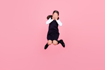 Fototapeta na wymiar Full length body size photo schoolgirl jumping up covering face with hands isolated pastel pink color background