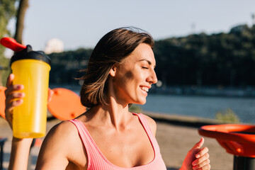 Sporty woman in fitting sport wear at sunset at outdoor sports ground positive posing enjoying...