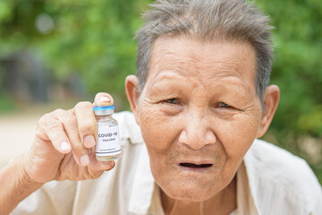 Old man holding a bottle of covid-19 vaccine.
