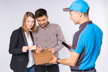 The man courier delivers home the box to the business lady with the husband, he signs for the delivery service and the wife paying using the card.