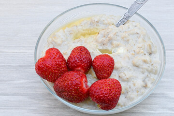 A plate of oatmeal porridge and ripe strawberries