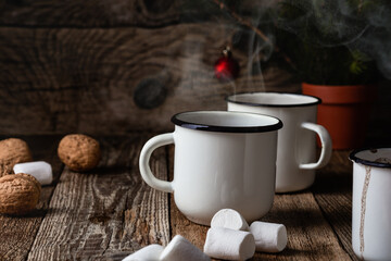 Hot cocoa in white mugs with  sweet marshmallows  on rustic wooden table