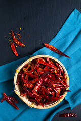 Food concept Dried Red Hot Chili, Chile peppers in bamboo wicker tray on black background with copy space