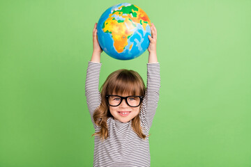 Photo of cool small blond hair girl hold globe up wear striped shirt isolated on green color backgound