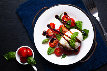 Healthy food concept rustic Caprese Salad on black background with copy space