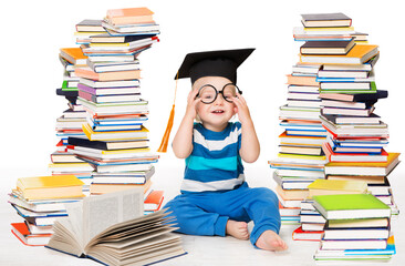 Little Baby Boy Reading Books. Happy Smiling Child in Graduation Cap Studying. Funny Kid wearing Glasses sitting next to Stack of Books over White Background