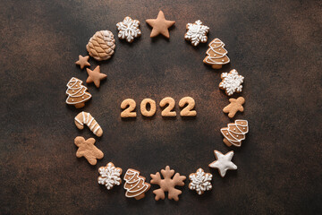 Obraz na płótnie Canvas Creative Christmas wreath of assorted cookies with date 2022 inside on a brown background. New Year greeting card. Top view. Xmas festive holiday.