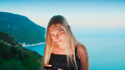 Woman using smartphone with ocean in the background. Vacations in warm countries.