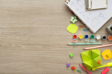 Top view of opened notebook and drawings in it,paint,pencils,markers and colorful bright stationery on the wooden school desk.Empty space