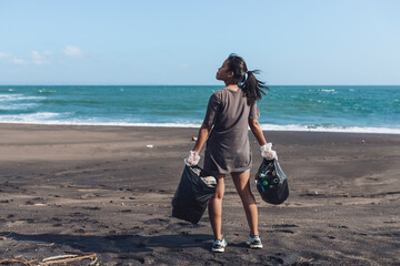 Asian woman cleans plastic from beach, volunteer concept..