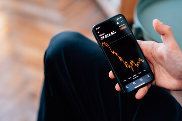 Selective focus shot of male hand holding a smartphone with cryptocurrencies statistics on screen © Tomáš Hustoles/Wirestock