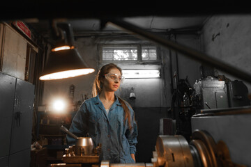 woman student works on an automatic lathe CNC, industrial workshop. Concept vocational education turner.