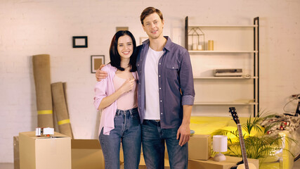 Fototapeta na wymiar happy couple smiling and standing near boxes in new home