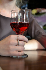 A girl holds a glass of red drink in her hands, wedding rings on her hand, a holiday, indoors 