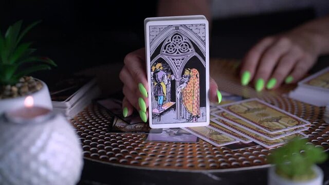 Blurred Fortune teller woman showing three of pentacles, reading a future by tarot cards. Esoteric concept, fortune-telling and predictions.  
