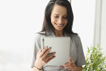 Smiling young woman in suit holding digital tablet