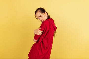 One young Caucasian woman in red casual clothes posing isolated on yellow background.