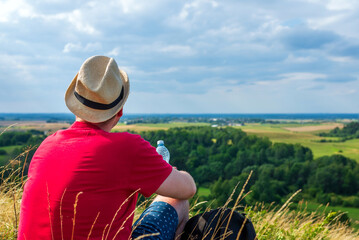 Traveler drinks water in the mountains.Hiker with backpack relaxing on top of the mountain in summer sunny day.