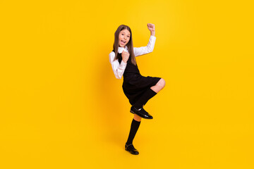 Full length body size photo schoolgirl in uniform gesturing like winner isolated bright yellow...