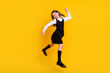Full length body size photo schoolgirl in uniform jumping gesturing like winner isolated bright...