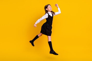 Fototapeta na wymiar Full length body size side photo schoolgirl in uniform jumping gesturing like winner isolated vivid yellow color background