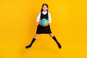 Fototapeta na wymiar Full length body size photo small schoolgirl jumping up keeping globe at school isolated vivid yellow color background