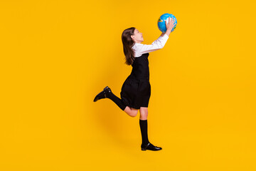 Fototapeta na wymiar Full length body size photo small schoolgirl jumping with globe on geography lesson isolated vivid yellow color background