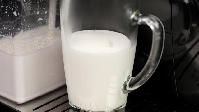 close-up of the process of filling hot milk in an automatic coffee machine in a transparent glass