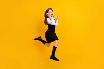 Fototapeta na wymiar Full size photo of brunette little small girl jump wear uniform formalwear long socks talk phone empty space isolated on yellow color background