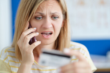 Surprised upset woman talking on mobile phone and holding bank card