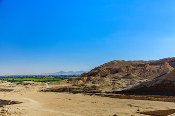 Fototapeta na wymiar Archeological site near the temple of Hatshepsut in Luxor, Egypt. Green landscape on a background