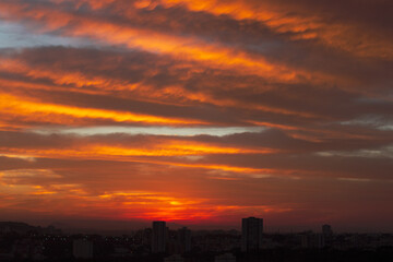 Sunrise skyline with red color fire on a cloudy winter day on a city. Space for text.