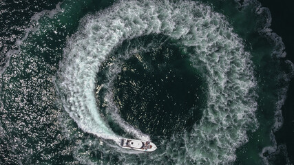 An aerial view of a boat sailing in a circle essentially making a donut in the ocean. 