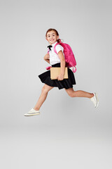 cute happy schoolgirl jumping up with backpack