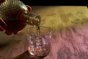hand serving whiskey in bar with colored lights