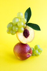 Balance of nectarines and green grapes on the yellow  background.Close-up. Location vertical.
