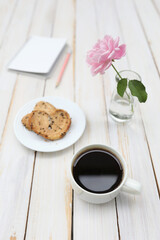Espresso black coffee cup with pie and rose with notepad on old vintage wooden table