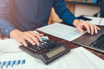 accountant working and analyzing financial reports and use calculator on office desk. finance and business concept.