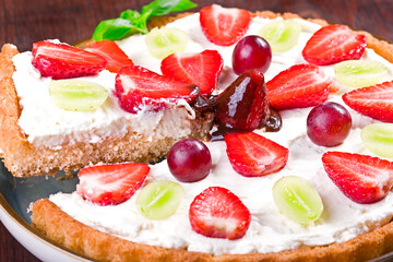 cake with cream, strawberries and grapes, topped with chocolate