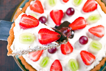 cake with cream, strawberries and grapes, topped with chocolate