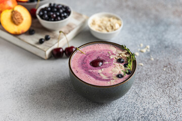 Smoothie bowl with blueberry, almond slices with fresh berries and fruit on wooden cutting board.