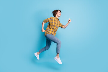 Fototapeta na wymiar Profile photo of carefree sporty lady jump run fast wear plaid shirt jeans sneakers isolated blue color background