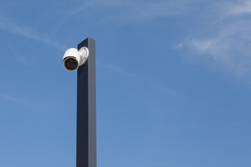 Singiel white modermSecurity cctv cameras in front of blue sky.