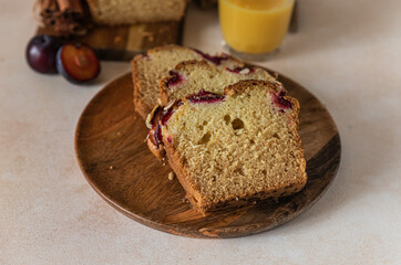 Homemade spicy plum cake decorated with almond on a wooden serving board, concrete background. Loaf cake with plum, spices and almond.