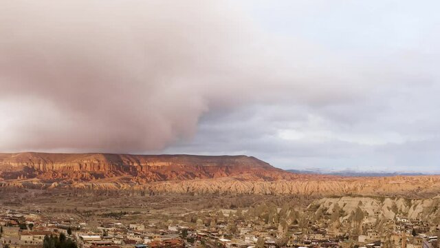 Aerial view from drone of mountains and rocks in Cappadocia near Goreme, Turkey. Action. Beautiful rocky valley with houses on cloudy sky background.